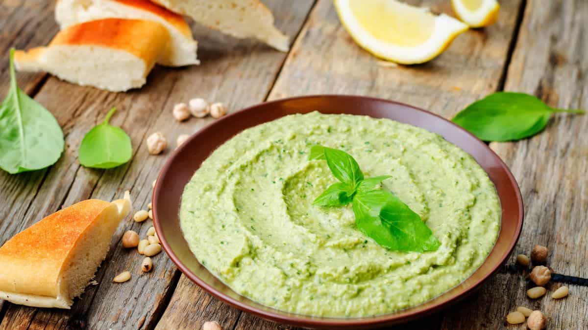 Pesto hummus in a brown bowl.