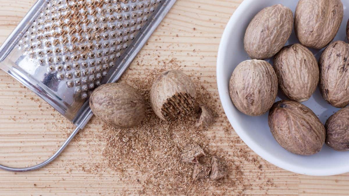 Grated and whole nutmeg with microplane in the background.