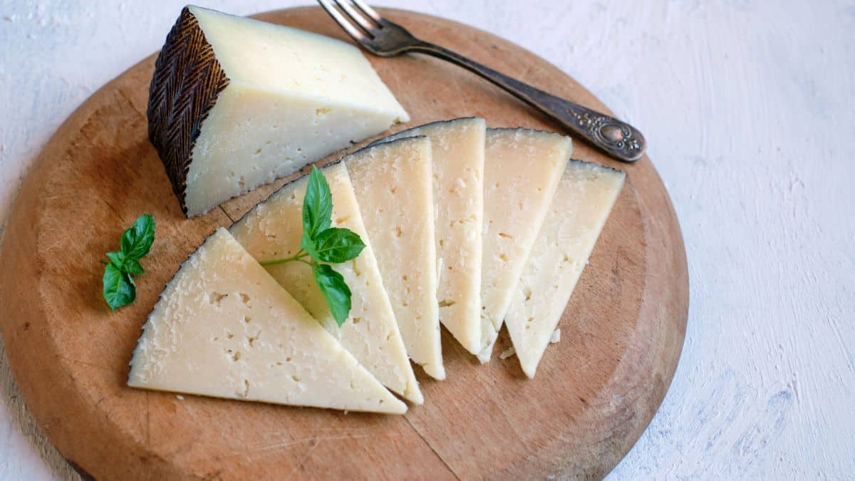 Manchego cheese pieces on a wooden board.