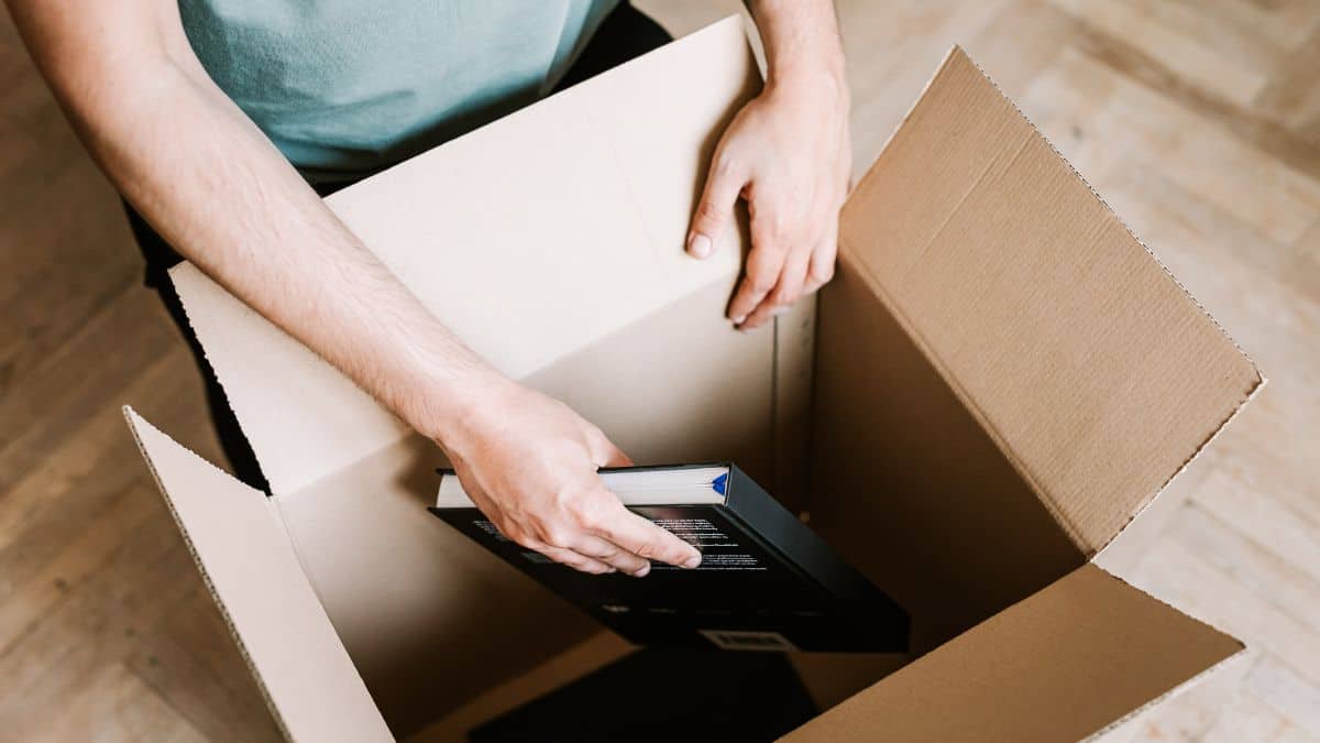 Man placing books in a carton box.