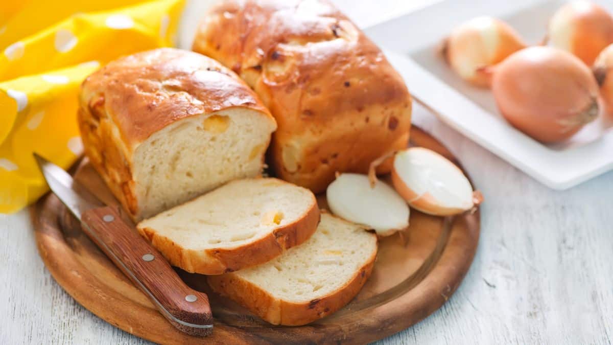 Whole and sliced onion bread on a wooden board.