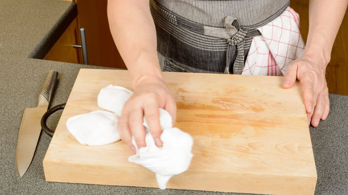 Person cleaning wooden cutting board.