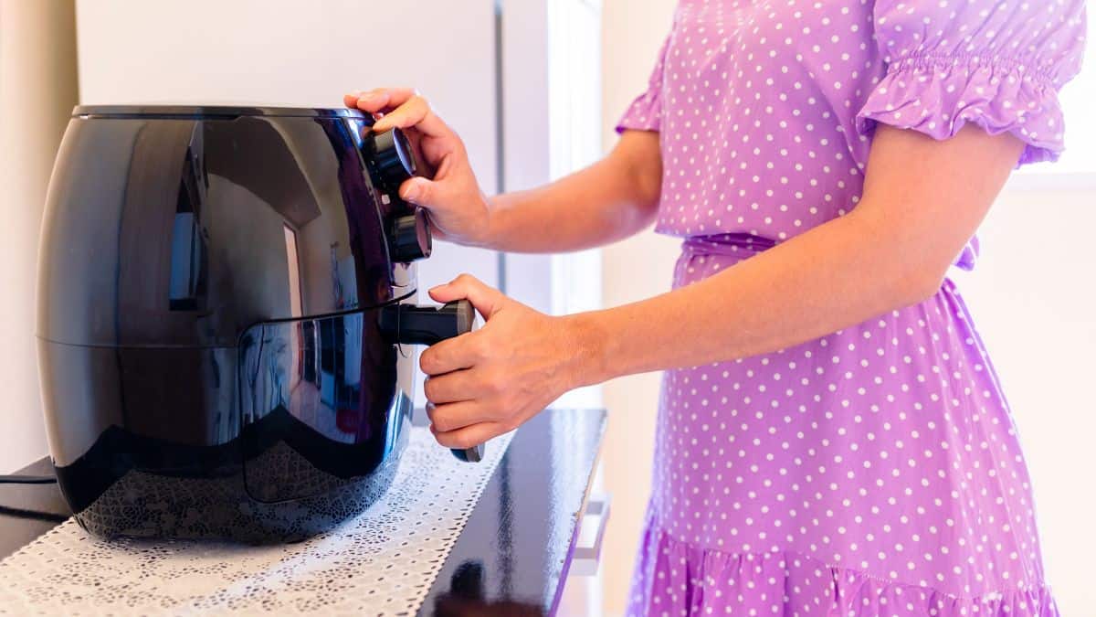 Woman preheating an air fryer.