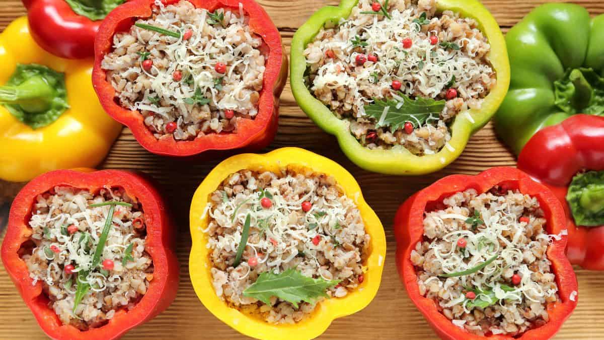 Rice-stuffed bell peppers on a wooden board.