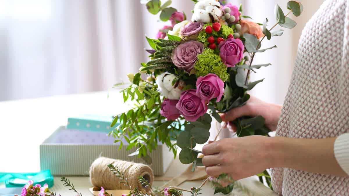 Woman removing extra leaves from cut flowers.