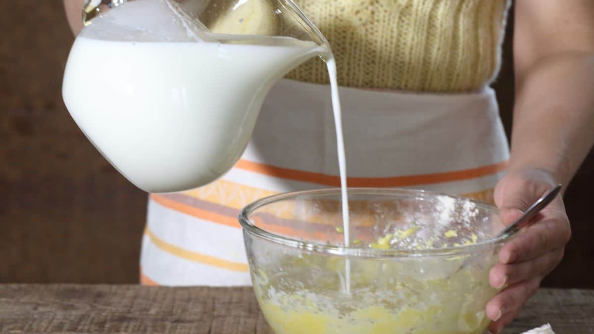 Woman adding milk into cake batter.