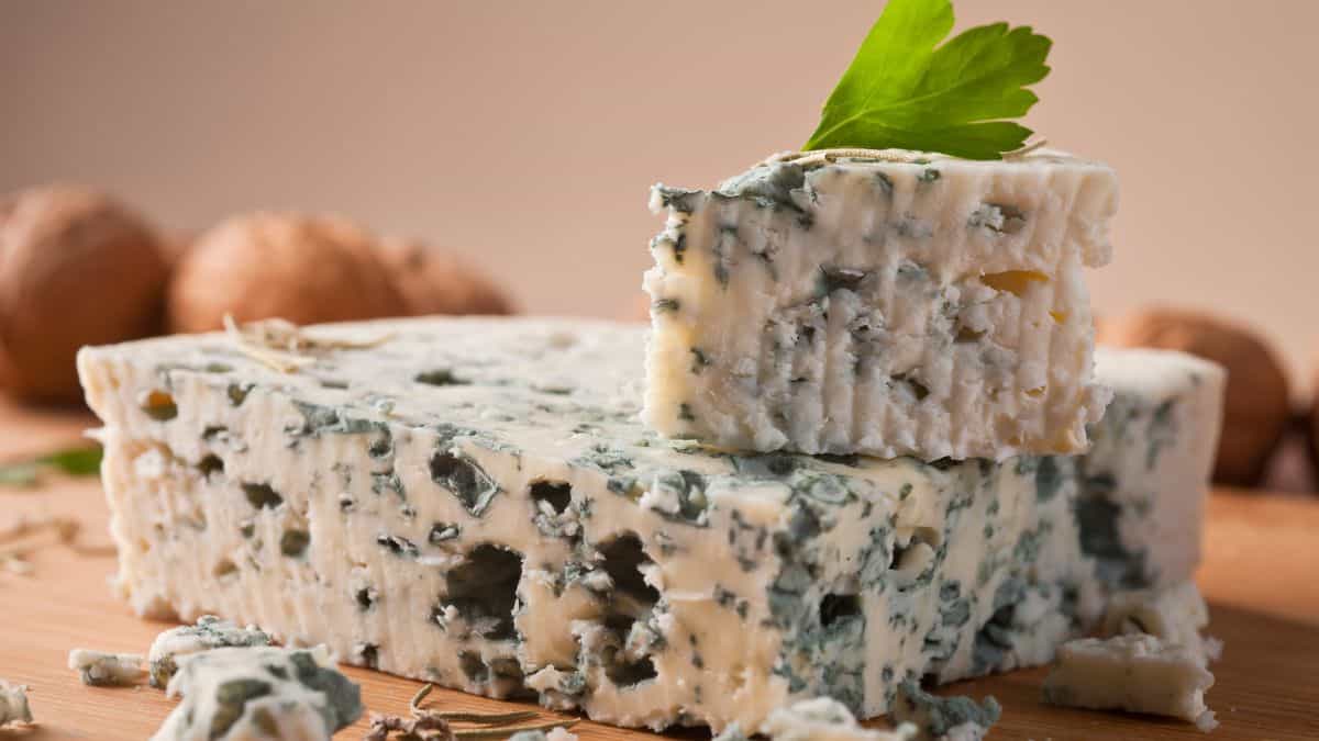 Blocks of roquefort cheese on a wooden board.