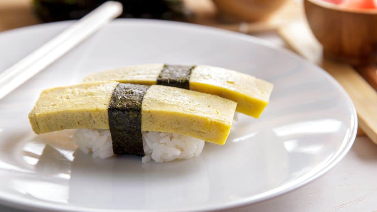 Takago nigiri or egg sushi on a white plate.