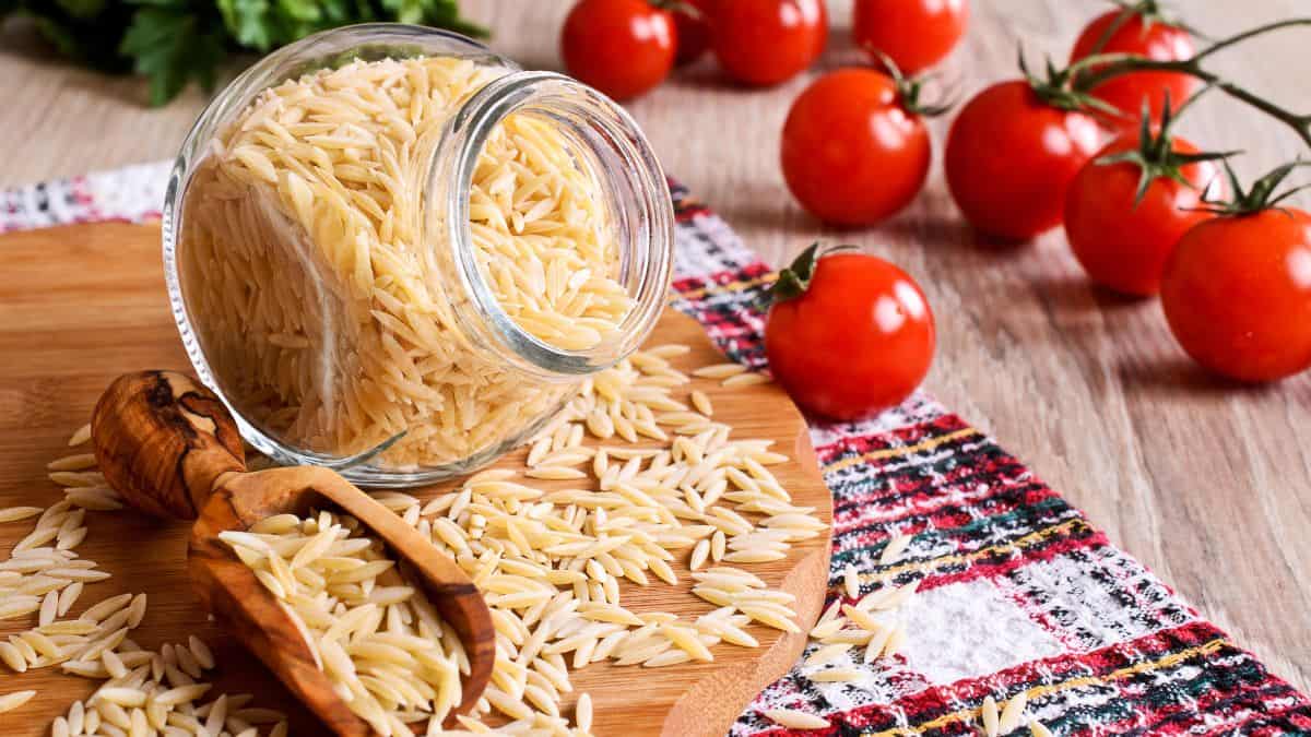 Orzo pasta with tomatoes in the background.