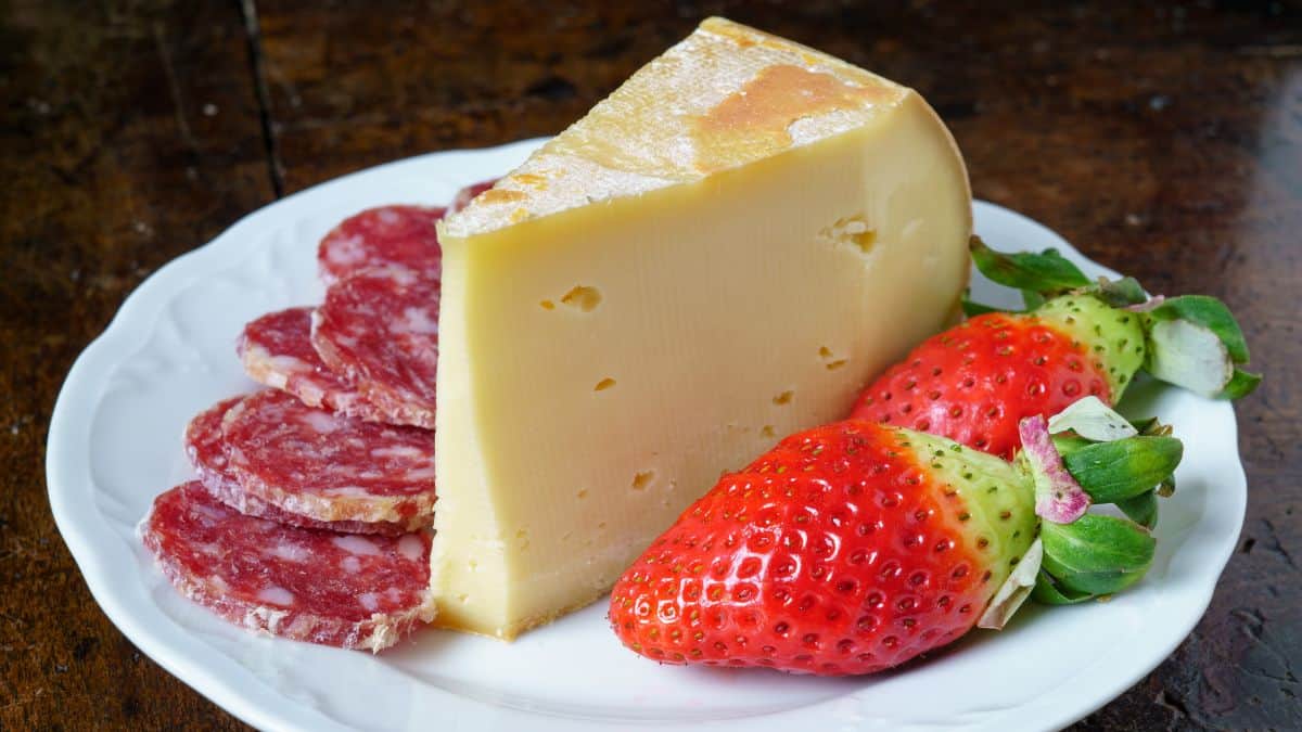 Fontina cheese served with berries on a white plate.