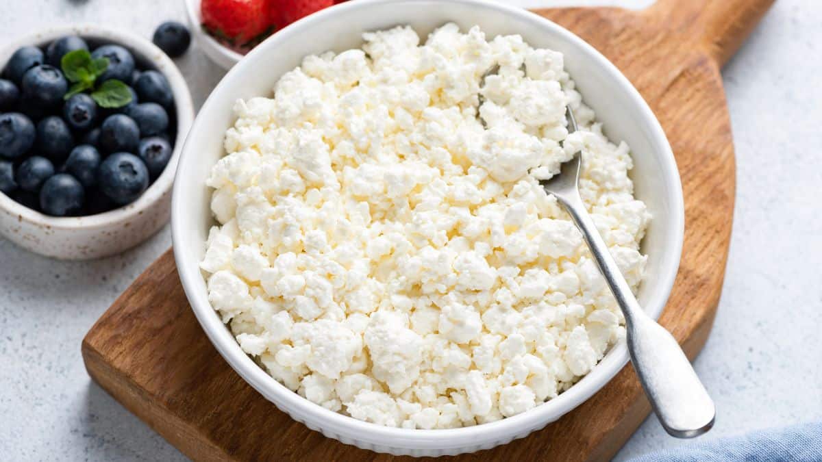 A bowl of cottage cheese with berries in the background.