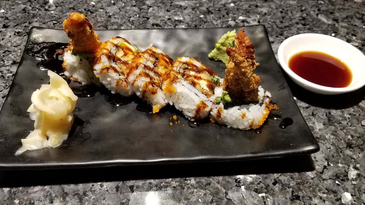 A plate of spider roll with sauces in the background.