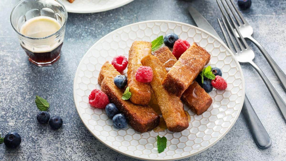 French toast sticks on a plate topped with berries.