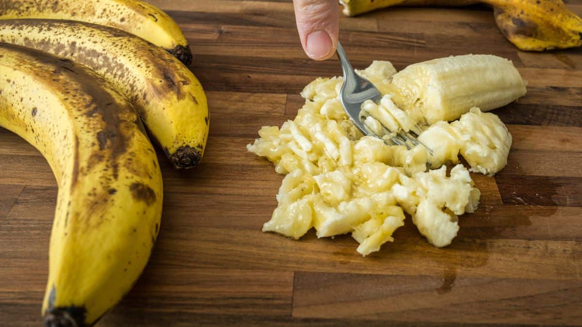 Person mashing banana using a fork.