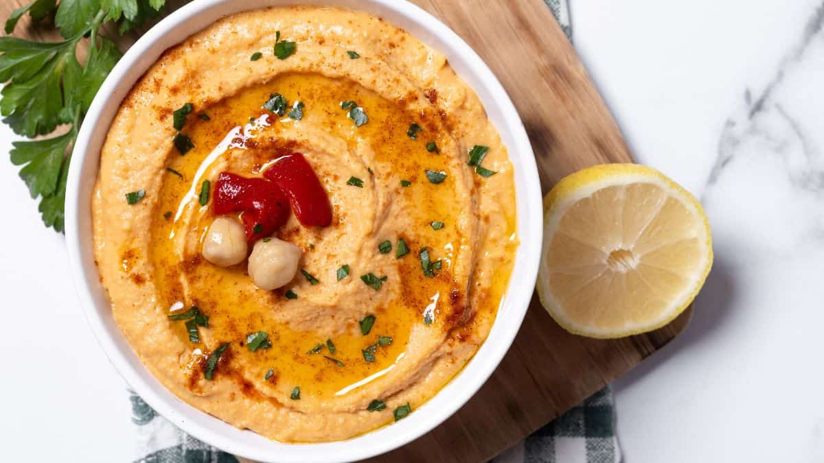 Red bell pepper hummus in a white bowl.