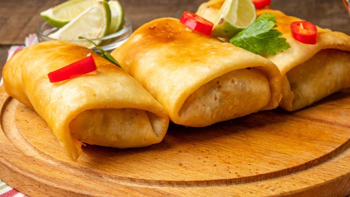 Crispy fried burritos on a wooden board.