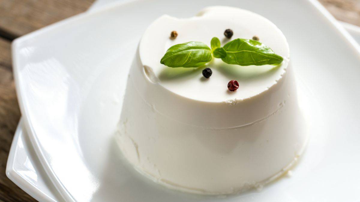 A block of ricotta salata on a white plate.