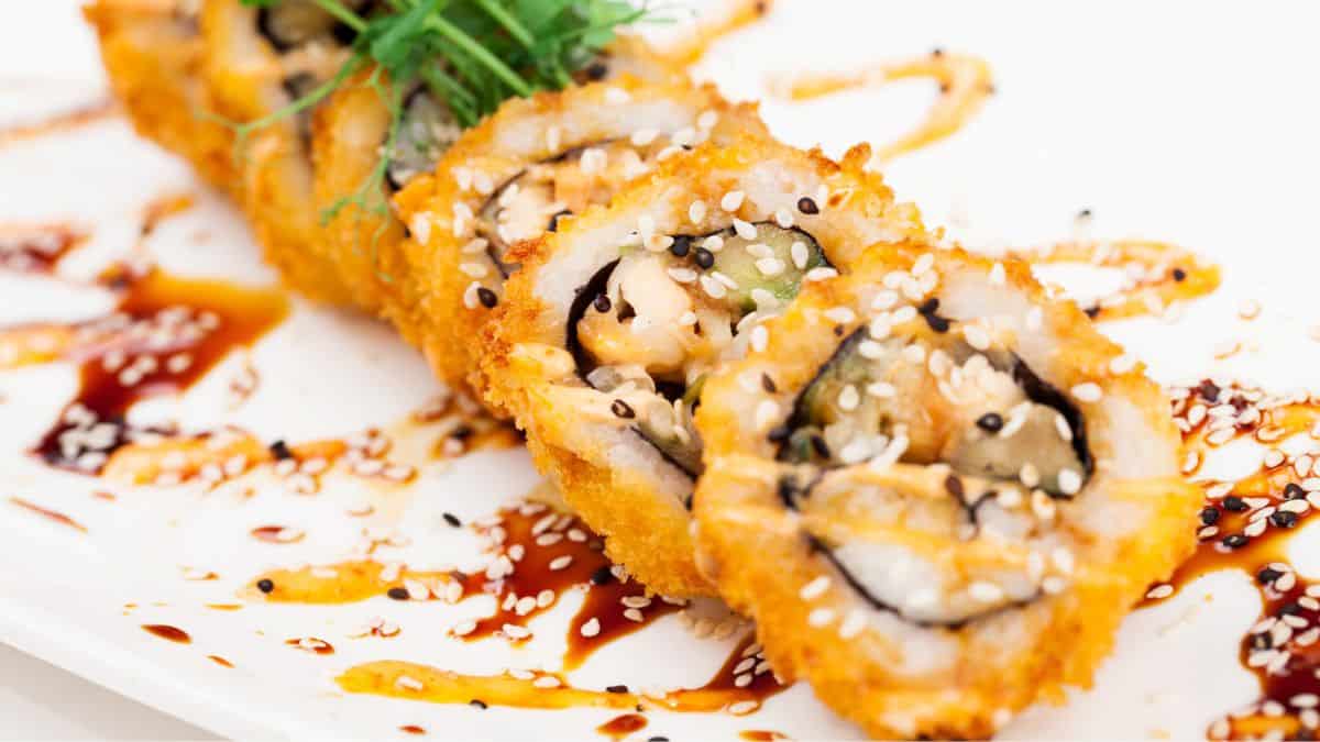 Crunchy roll drizzled with saucd on a white plate.