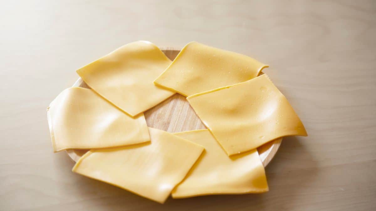 Slices of American cheese on a wooden plate.