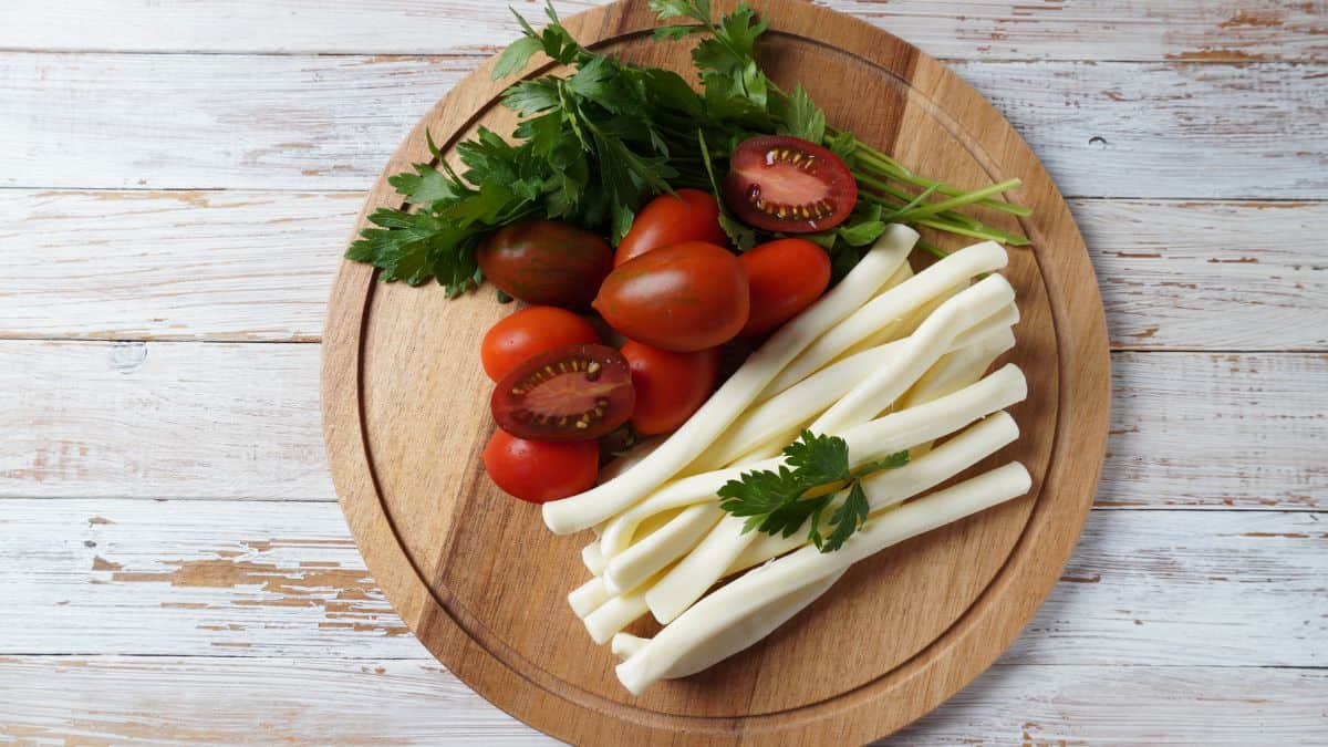 String chesse on a wooden board with tomatoes.