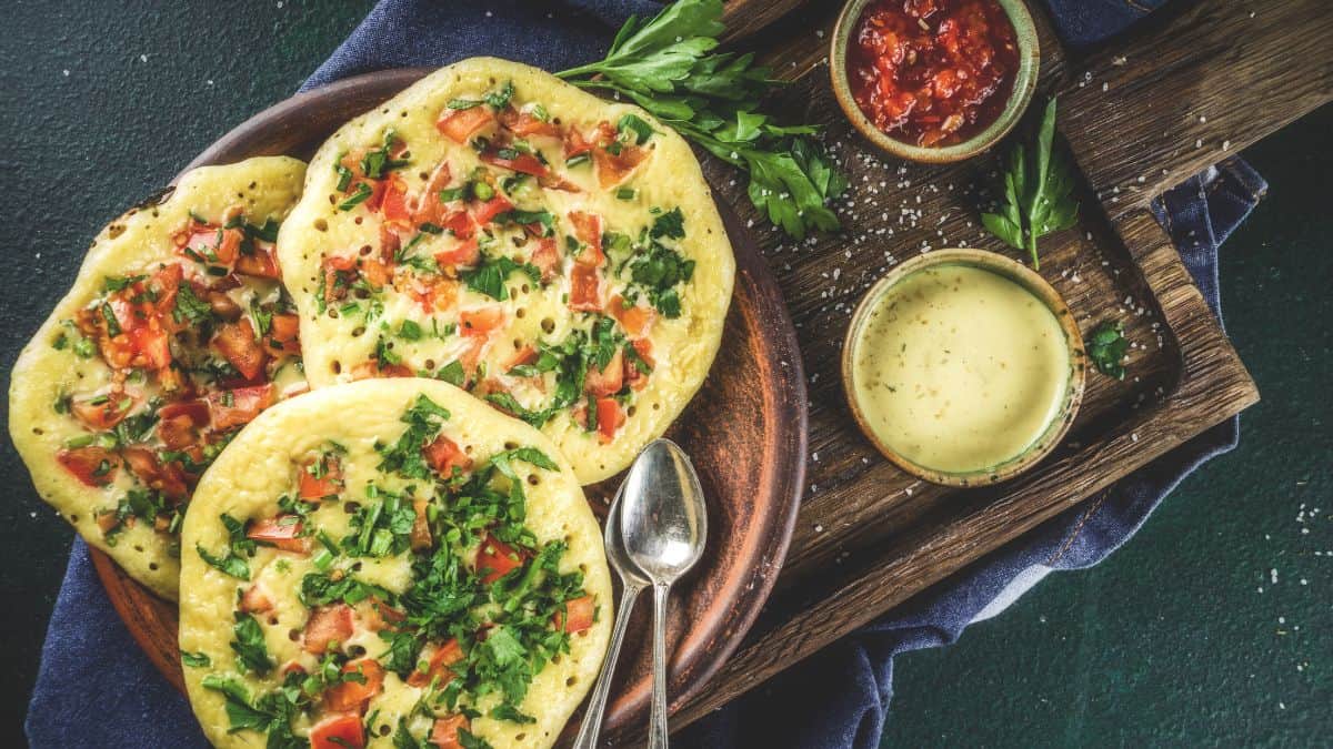 Uttapan served with chutney on a wooden board.