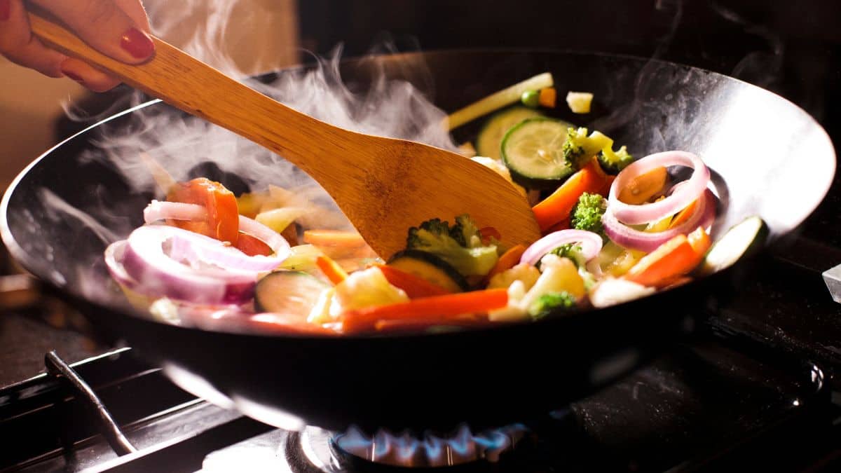 Stir fry vegetables in a wok.