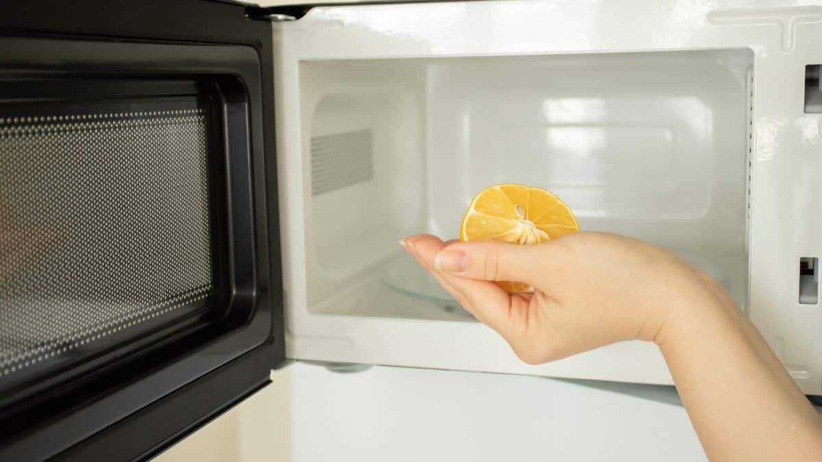 Woman placing lemon in microwave.