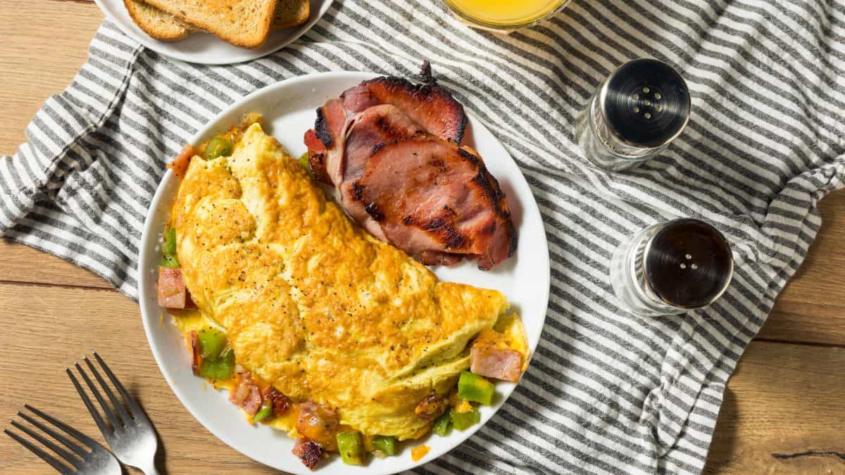 Denever omelet on a white plate served with bacon.