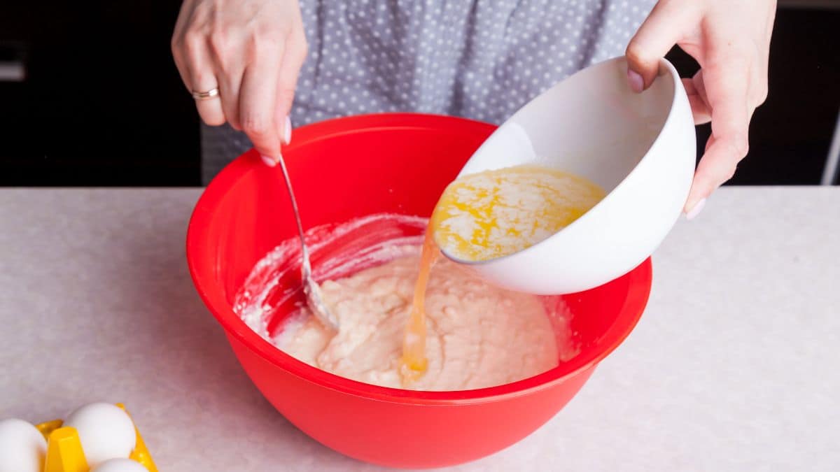 Woman adding melted butter into cake batter.