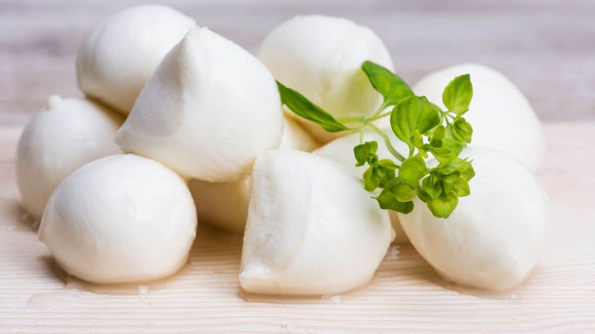 Balls of mozzarella cheese on a wooden board.