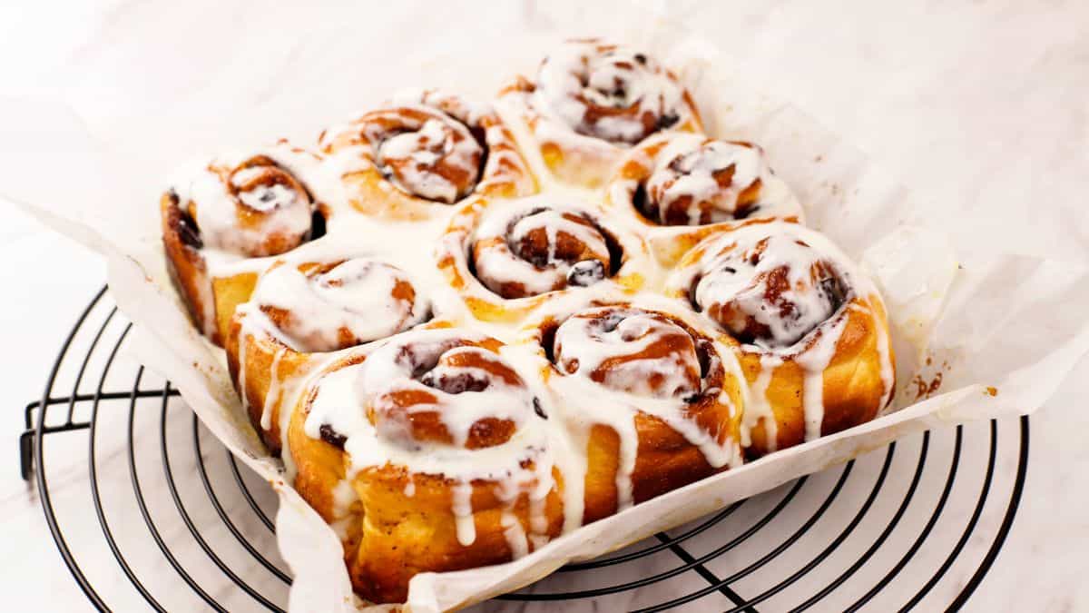 Cinnamon rolls drizzled with icing on a white plate.