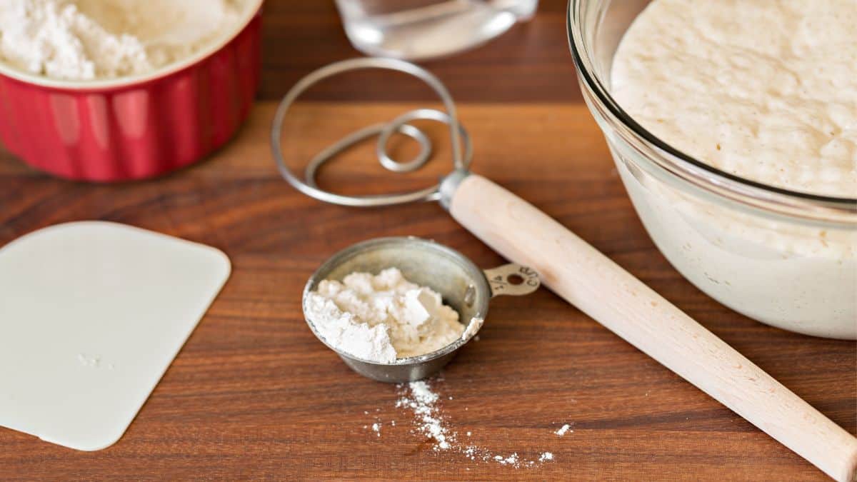 Dough whisk on a wooden board with flour.