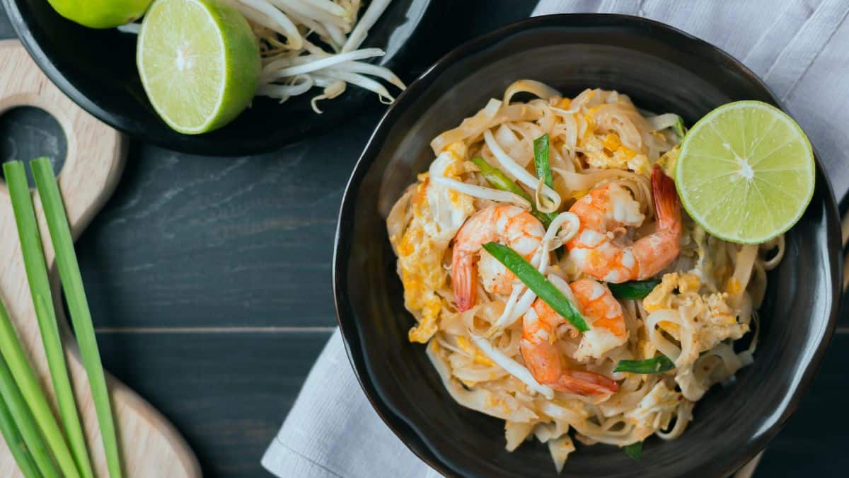 Shrimp pad thai noodles in a black bowl.