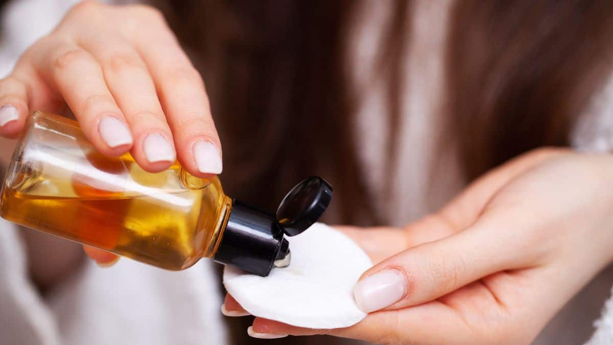 Woman pouring toner on a cotton pad.