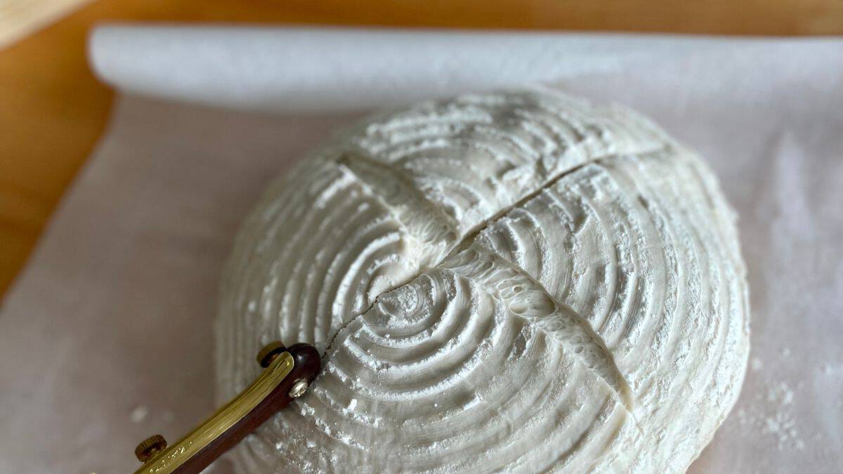 Person cutting dough using a bread lame.