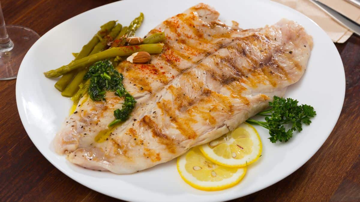 Two pieces of cooked fish on a white plate.