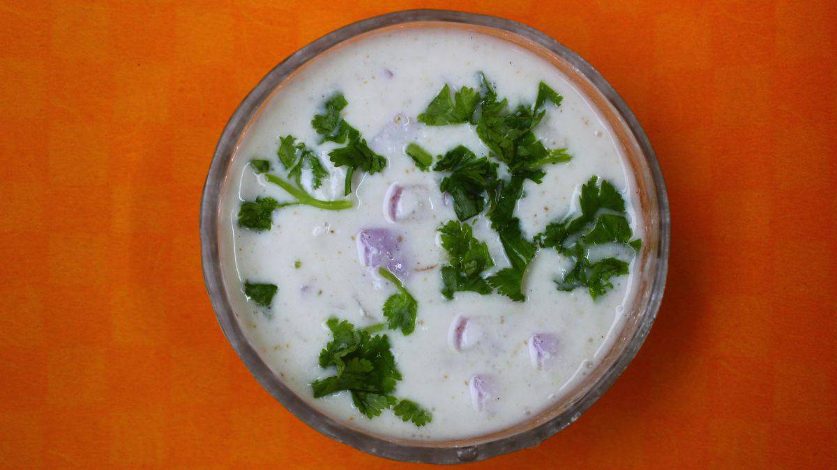 A bowl of onion raita on an orange surface.