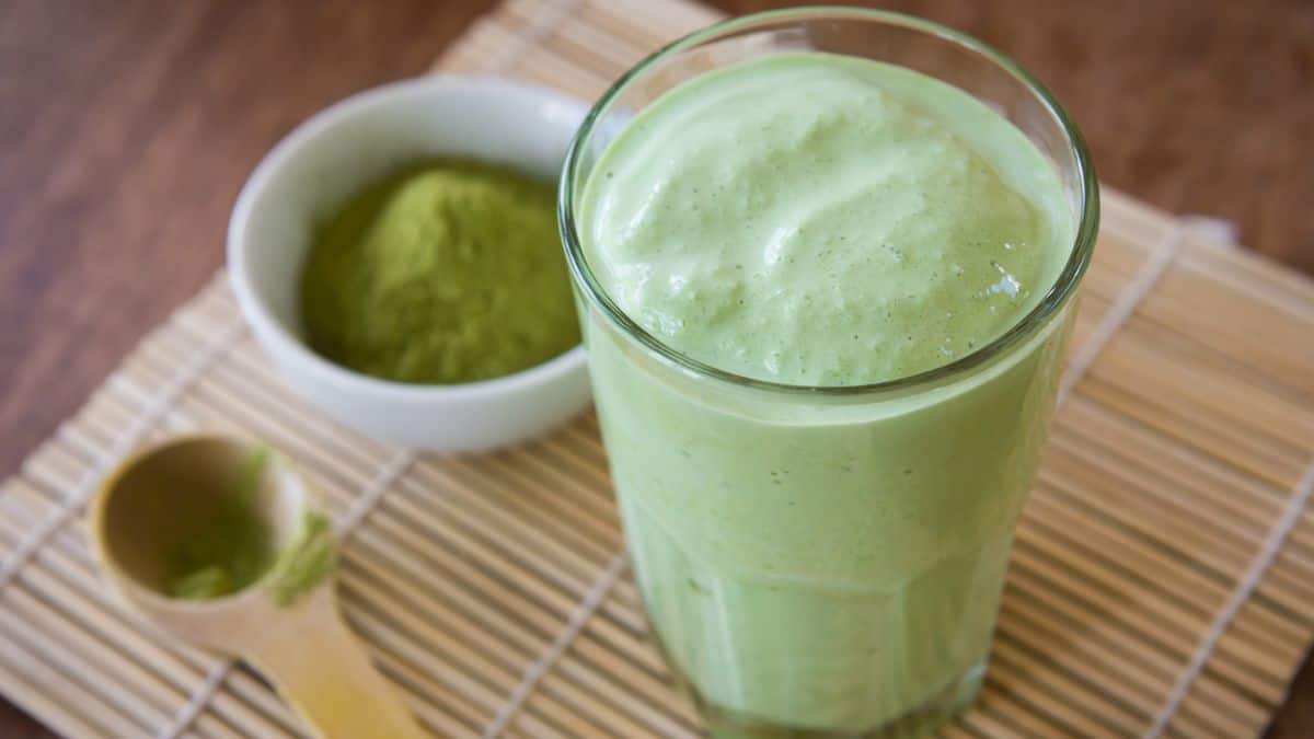 Matcha smoothie glass with matcha powder in the background.