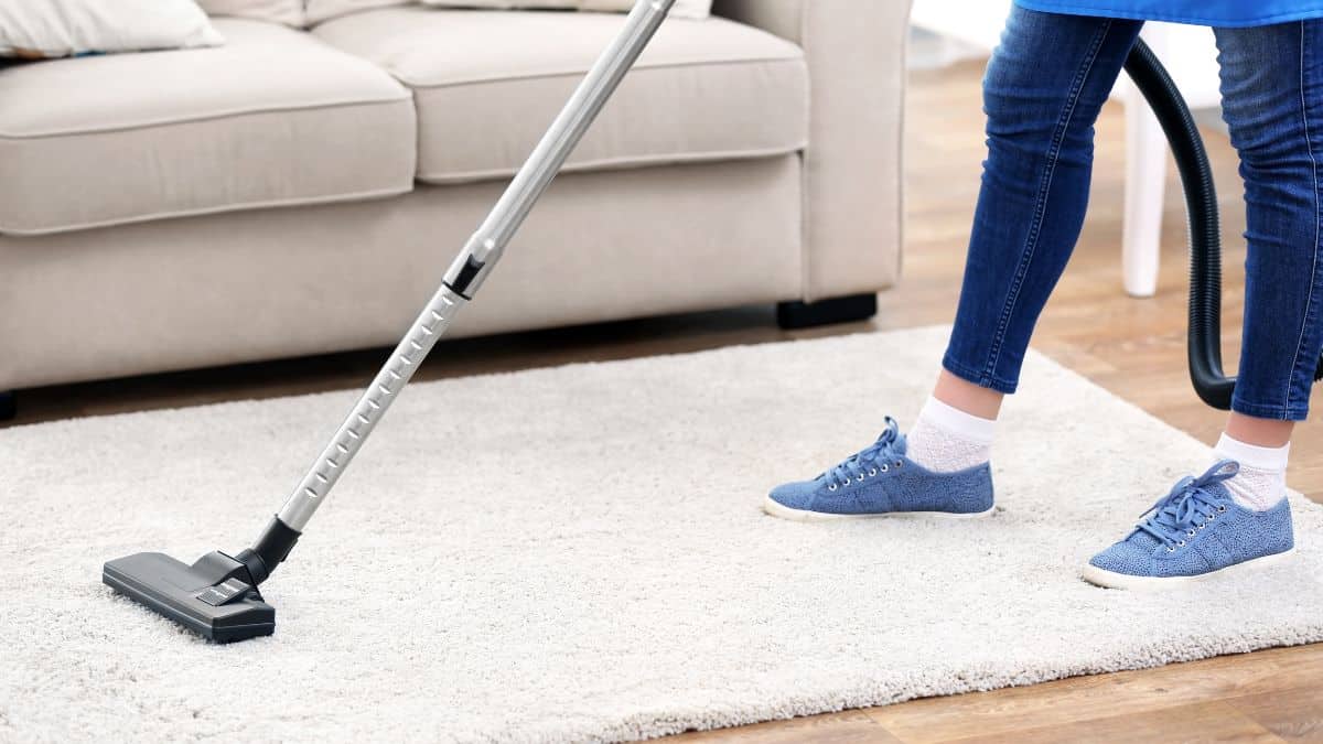 Woman vaccuming carpet.