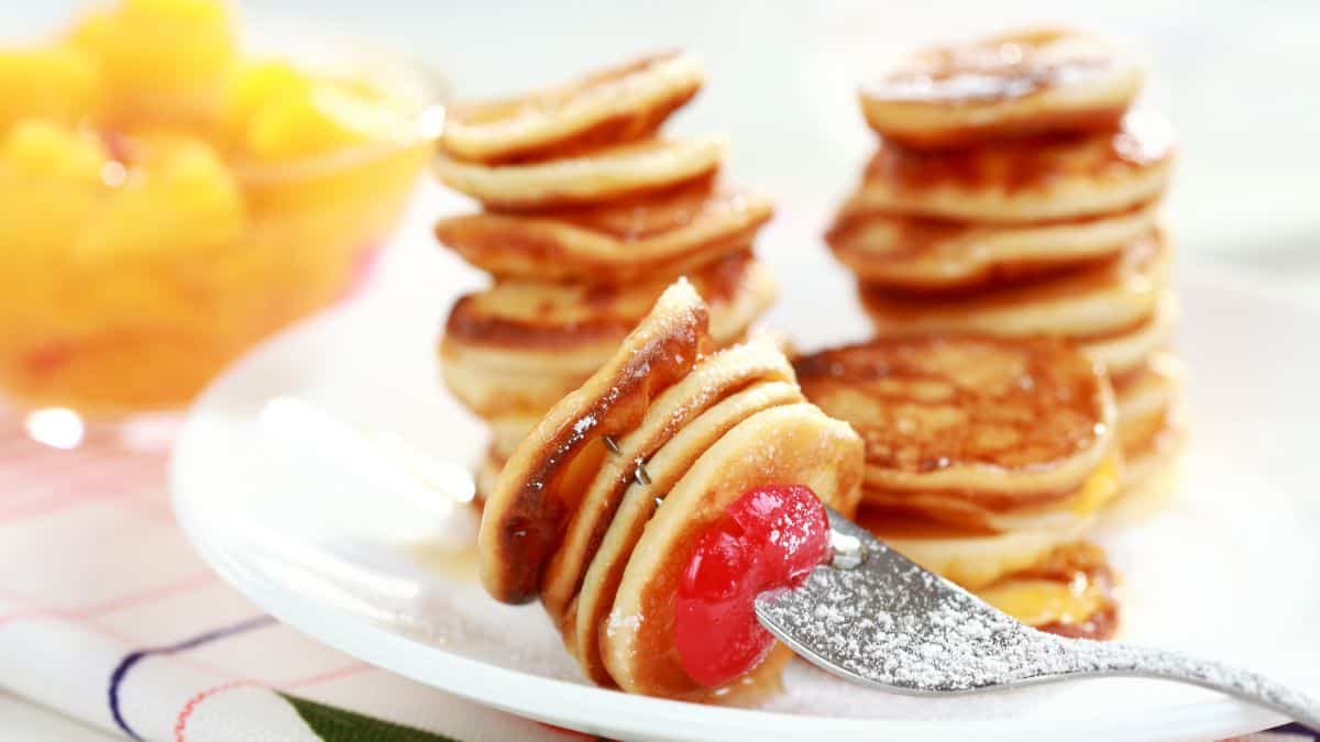 Stacks of mini pancakes on a white plate.