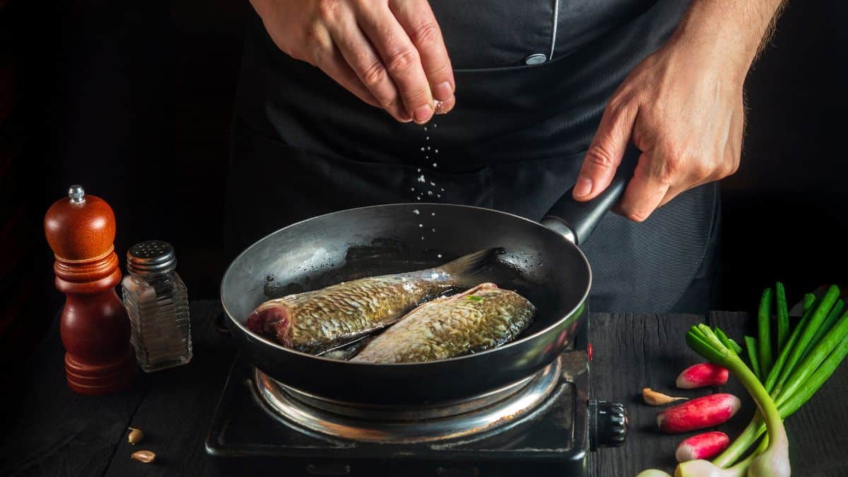 Fish in the pan being seasoned.