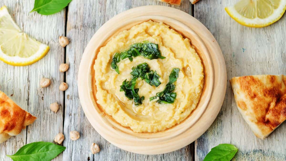 Basil hummus on a brown board.