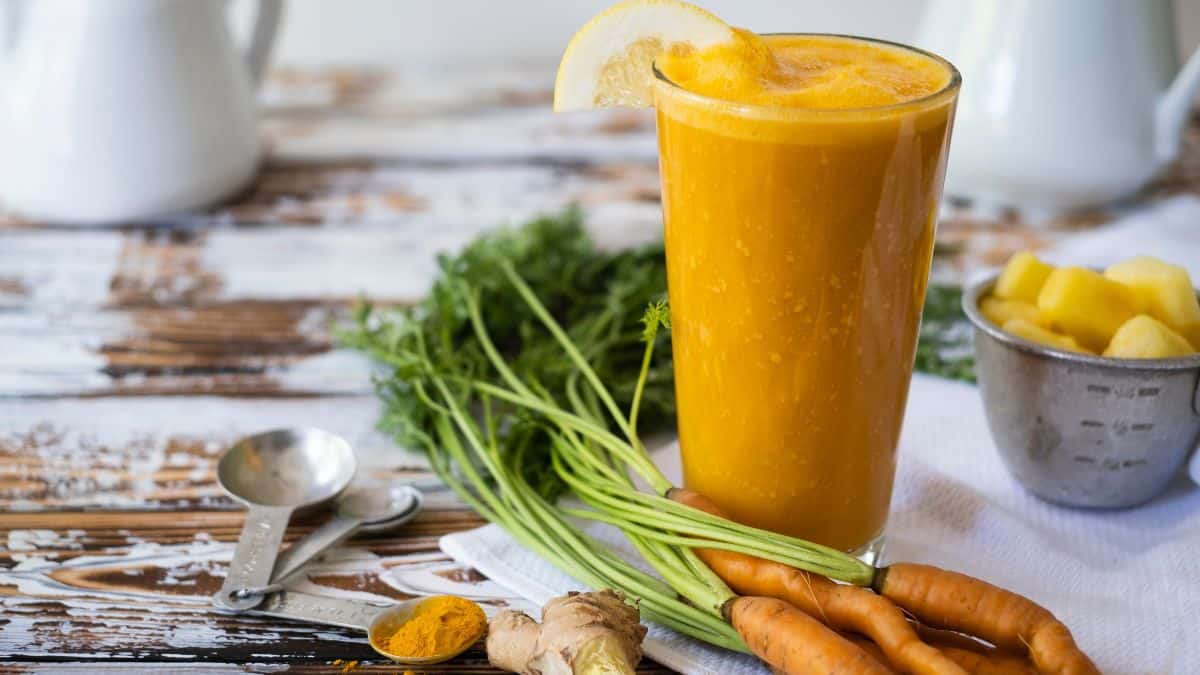 Turmeric, carrot and ginger smoothie in a tall glass.