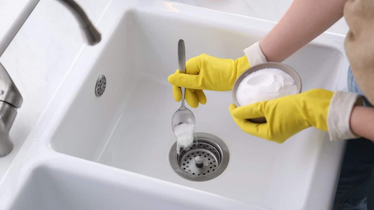 Pouring baking soda into drain.