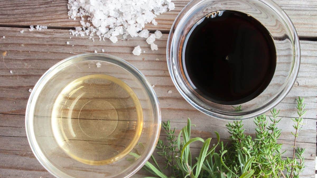 Two bowls of vinegar on a wooden board.