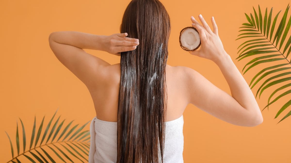 Woman applying coconut oil on hair.