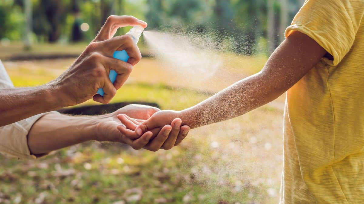 Woman giving bug spray to kids.