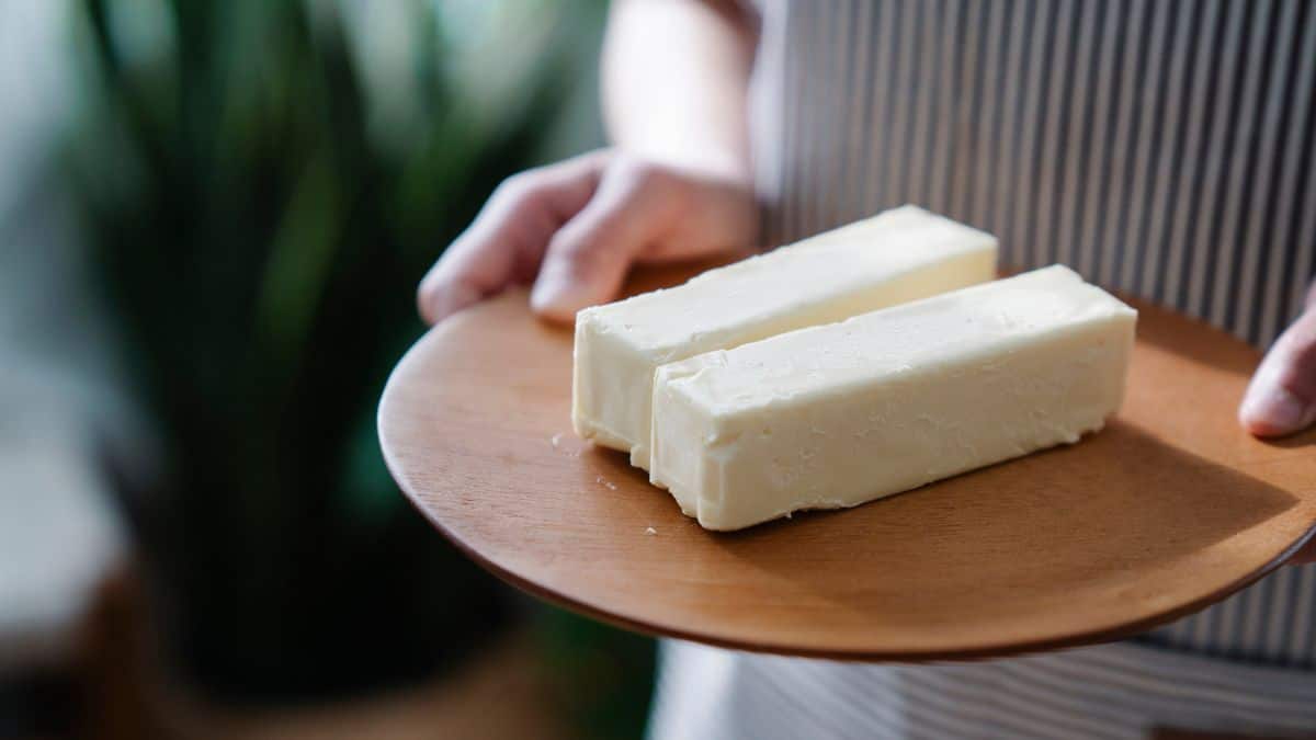 A person holding a plate with two sticks of butter.