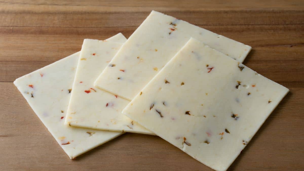 Pepper jack slices on a wooden plate.