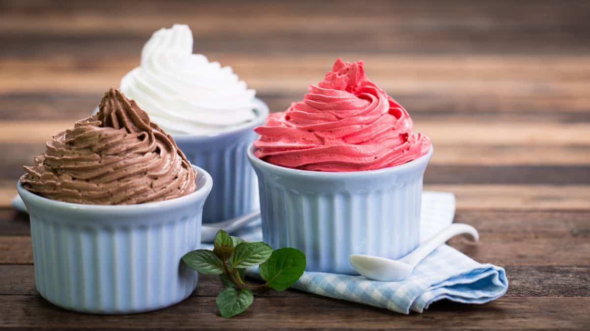 Three bowls of frozen yogurt on a wooden board.